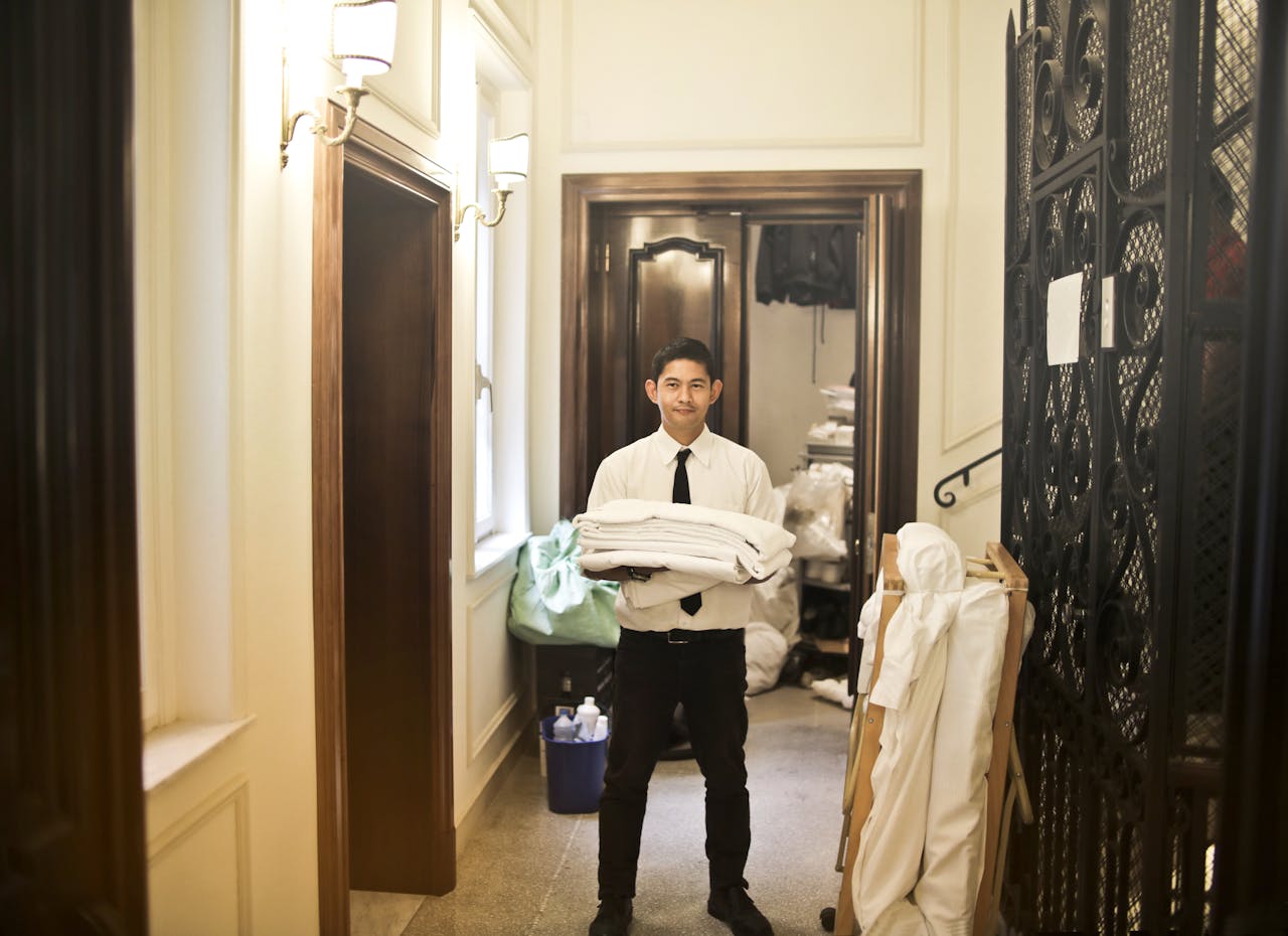 Professional hotel staff member carrying fresh linens in an elegant hallway.
